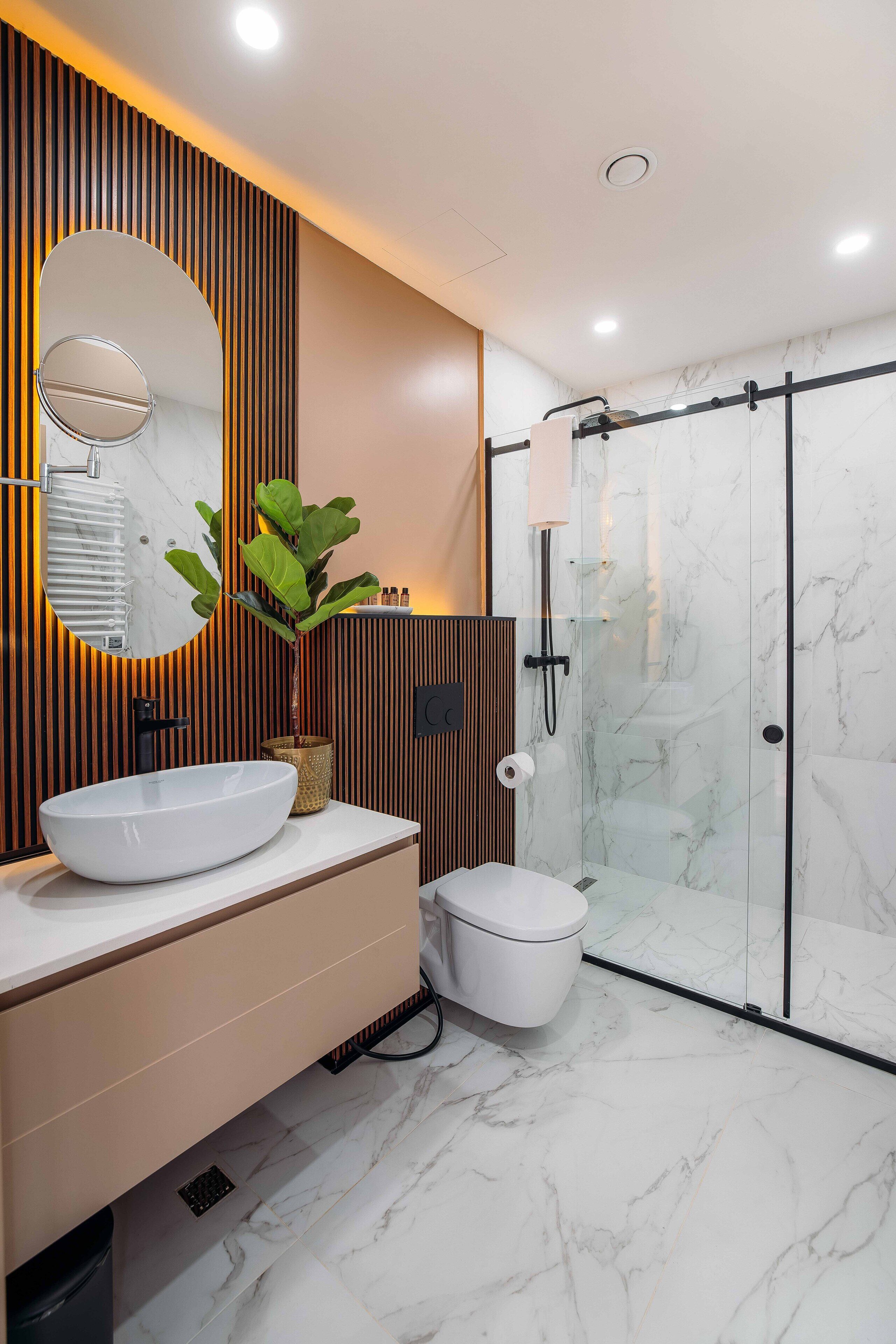 Une salle de bain moderne avec un lavabo blanc, des toilettes et une douche à parois de verre.
