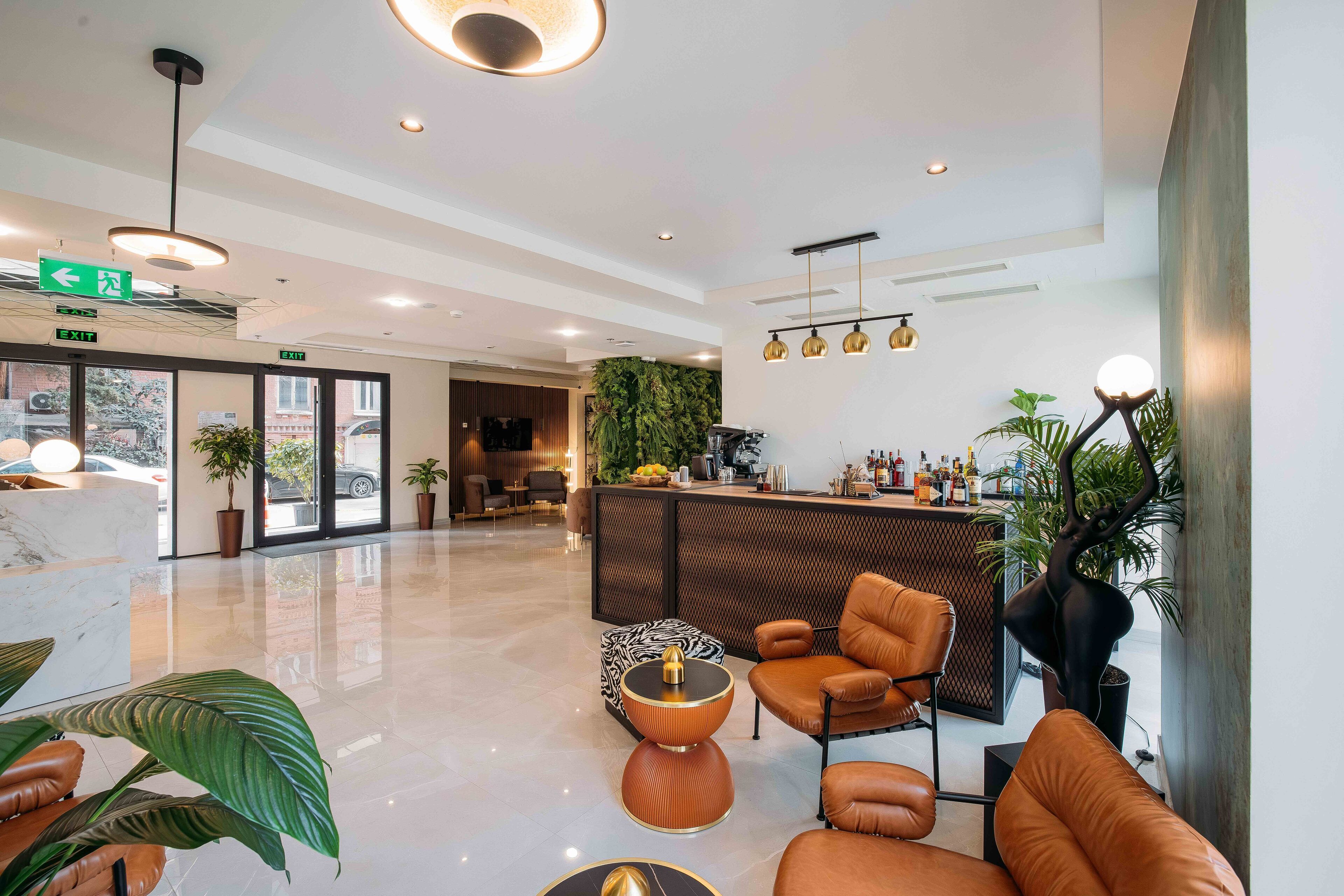 A modern lobby with a reception desk, seating area, and a large plant.