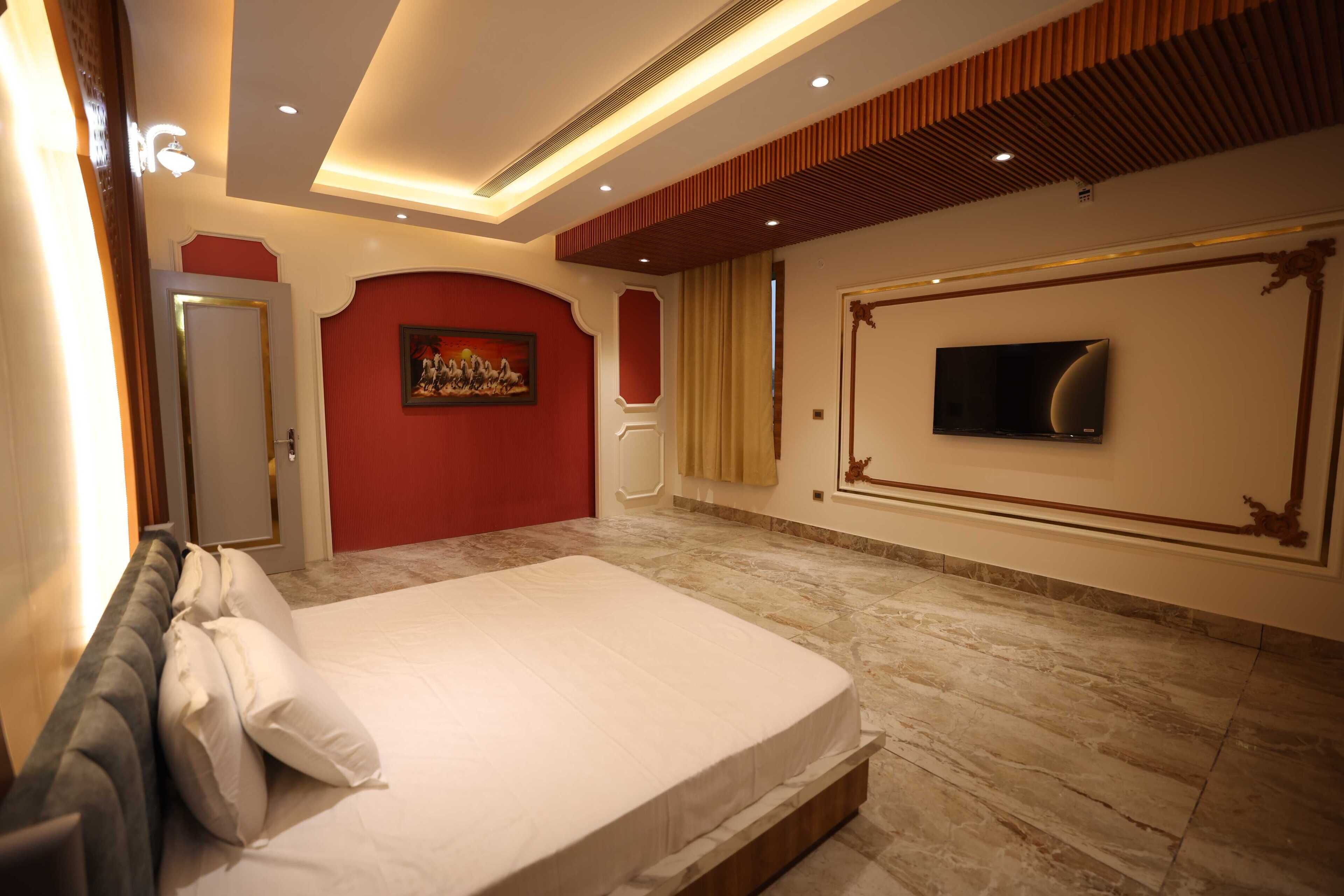 Une chambre d’hôtel avec un grand lit, une télévision et un mur d’accent de couleur rouge.