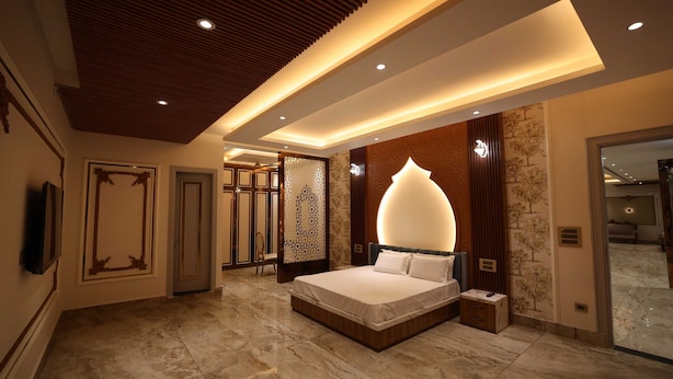 Een moderne slaapkamer met een groot bed, inbouwverlichting en een decoratief wandpaneel.