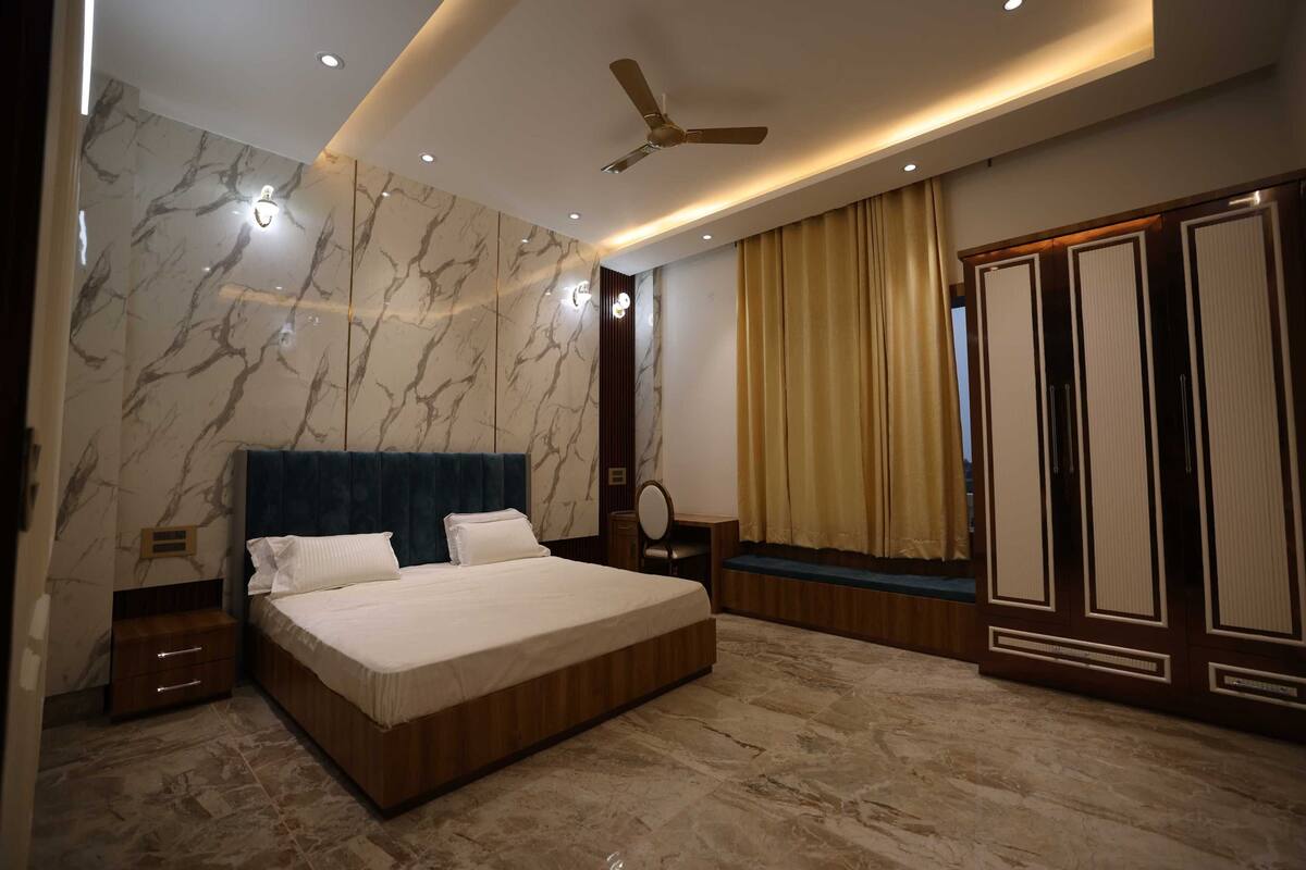A modern bedroom with a large bed, a ceiling fan, and a wardrobe.