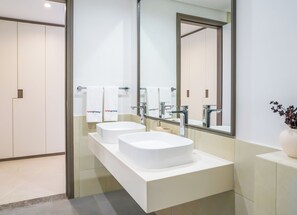 A modern bathroom with two sinks, a large mirror, and a vase with flowers. - HomesGetaway-2BR Apt in 1 Residences (Dubai)