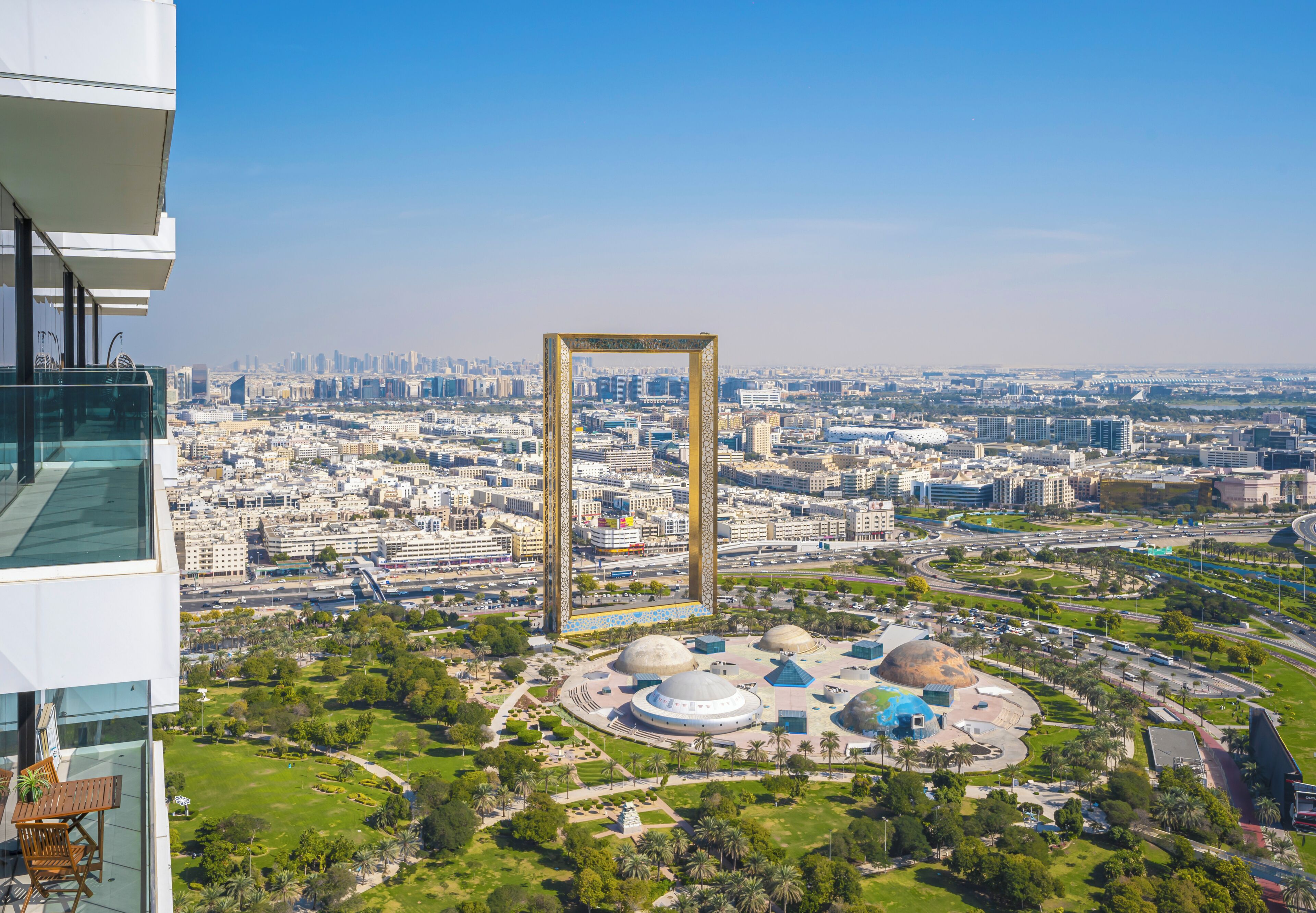 A high-rise building overlooking a cityscape with a large golden frame structure in the center.