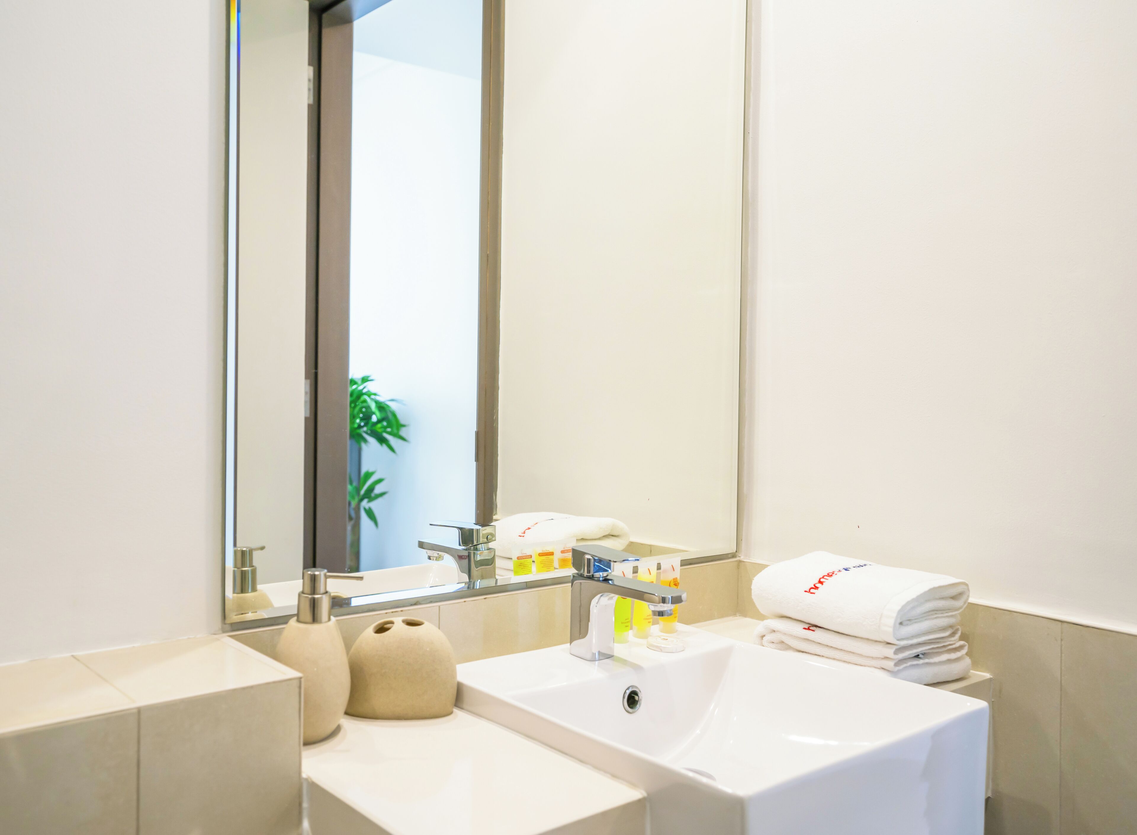 A modern bathroom with a white sink, two mirrors, and a towel rack.