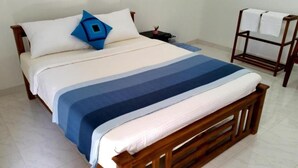 A bed with a striped bedspread, a wooden headboard, and a nightstand with a lamp. - Victoria Nature Resort Digana (Digana)