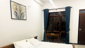 A bedroom with a bed, a wooden desk, a chair, a window with curtains, and a door. - Victoria Nature Resort Digana (Digana)