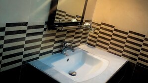 A bathroom with a white sink, a mirror, and a tiled backsplash. - Victoria Nature Resort Digana (Digana)