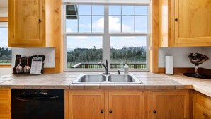 A kitchen with wooden cabinets, a double sink, and a view of a balcony with a railing. - Picturesque Vineyard and Valley Views, Quiet and Private Setting, Huge Deck, *Complimentary Wine* (Newberg)
