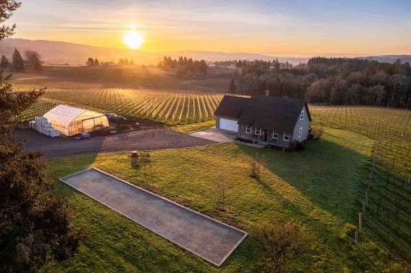 A rural landscape with a house and greenhouse.