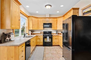A kitchen with wooden cabinets, a black refrigerator, a stove, and a microwave.