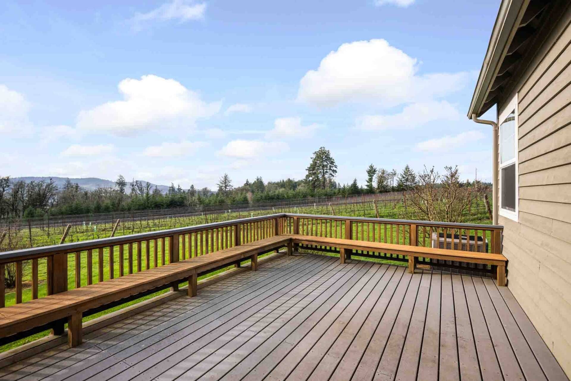 A wooden deck with a view of a vineyard and distant hills.