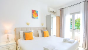 Habitación de hotel con una cama grande, una mesita de noche, un equipo de aire acondicionado y vistas al exterior.