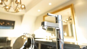 Een moderne badkamer met een chromen kraan, een ronde spiegel en een kroonluchter.