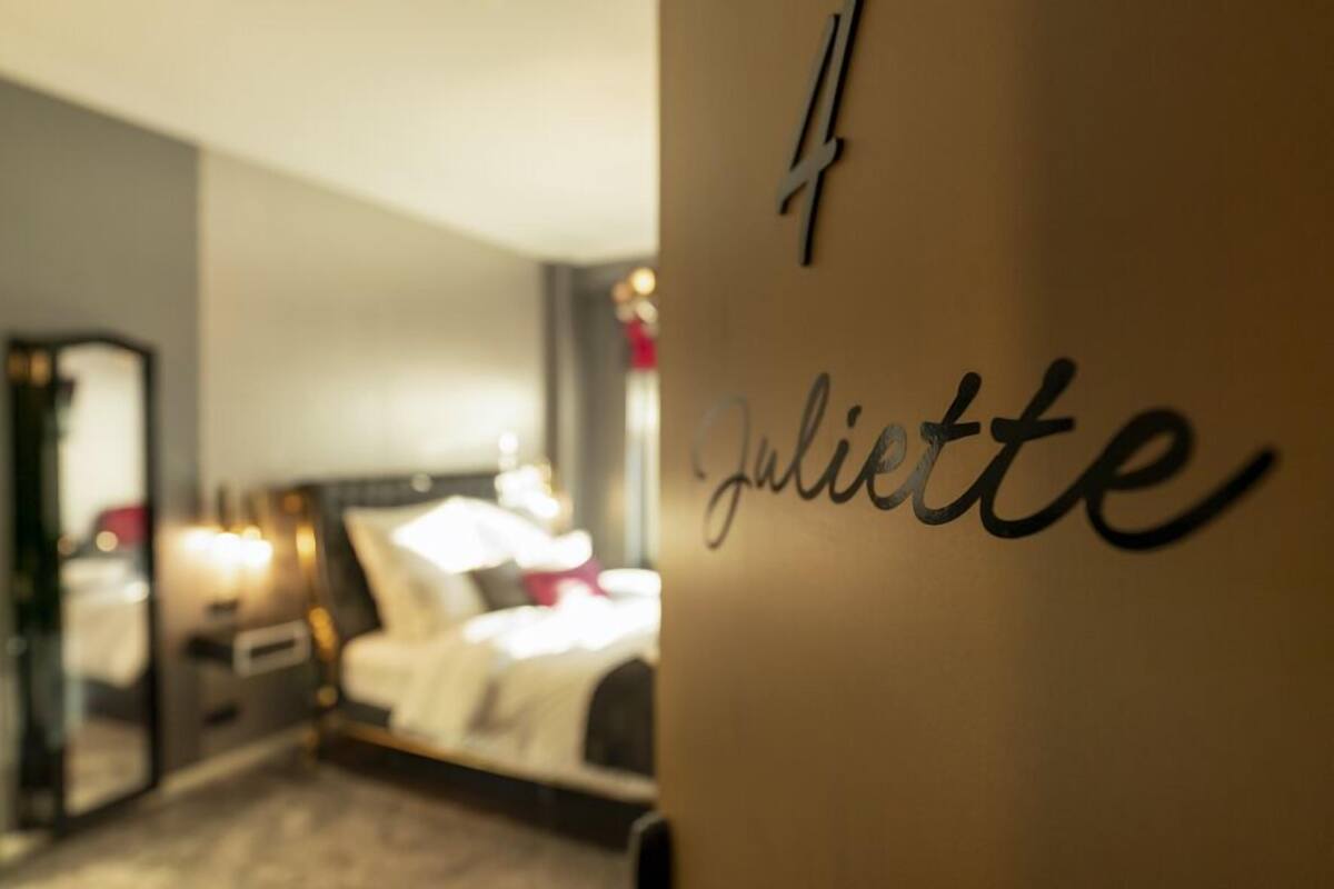 Habitación de hotel con una cama, una mesita de noche y una pared con el nombre 'Juliette' y el número '4'.