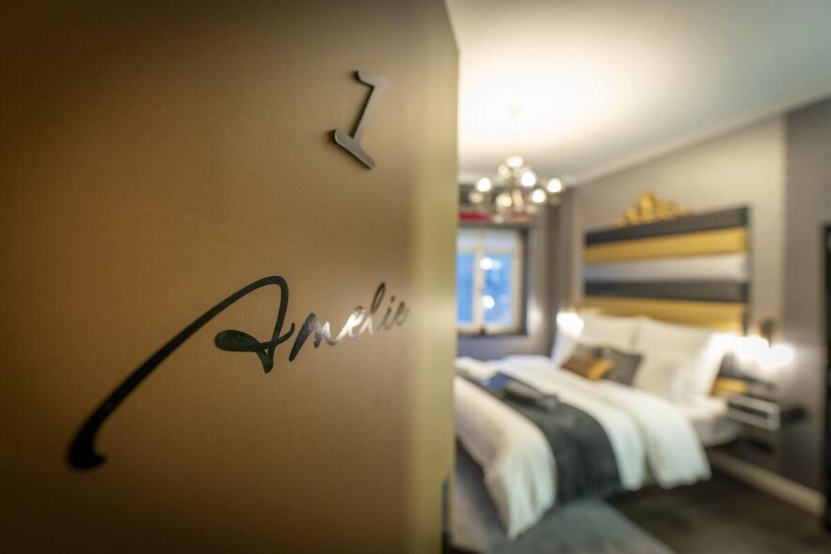 Una habitación con una cama, una mesita de noche y una pared con un número y un nombre.