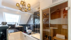 Een moderne badkamer met een ruim bad, een douche met glazen wanden en een houten sauna.