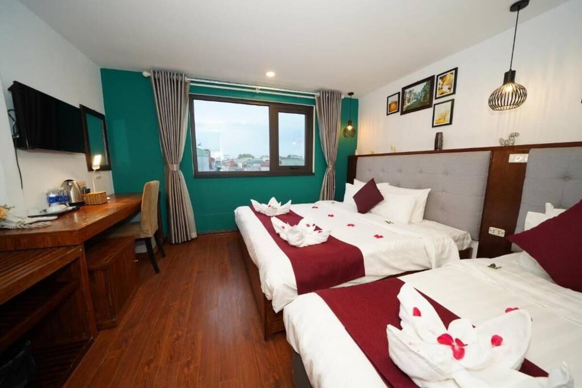 Habitación de hotel con dos camas, un escritorio, un televisor y una ventana con cortinas.