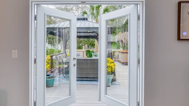 Puerta de cristal que da a un patio exterior con plantas en macetas y una pérgola.