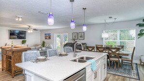 Una cocina moderna con una isla central, electrodomésticos de acero inoxidable e iluminación colgante.