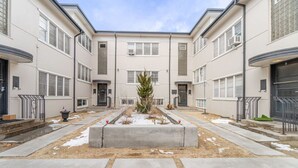 A courtyard with a central planter, surrounding buildings with multiple windows, and a clear sky. - Riverside Luxe: Stylish Designer Retreat (Reno)