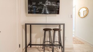 A modern kitchen with a cityscape artwork above a black metal table and two stools. - Riverside Luxe: Stylish Designer Retreat (Reno)
