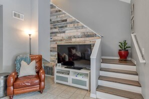 Ein Wohnzimmer mit Kamin, Ledersessel, Fernseher und Treppe.