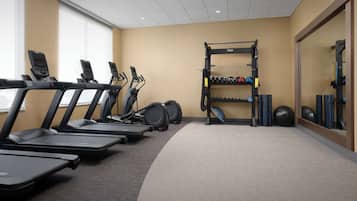 A gym with treadmills, elliptical machines, a squat rack, and various weights.