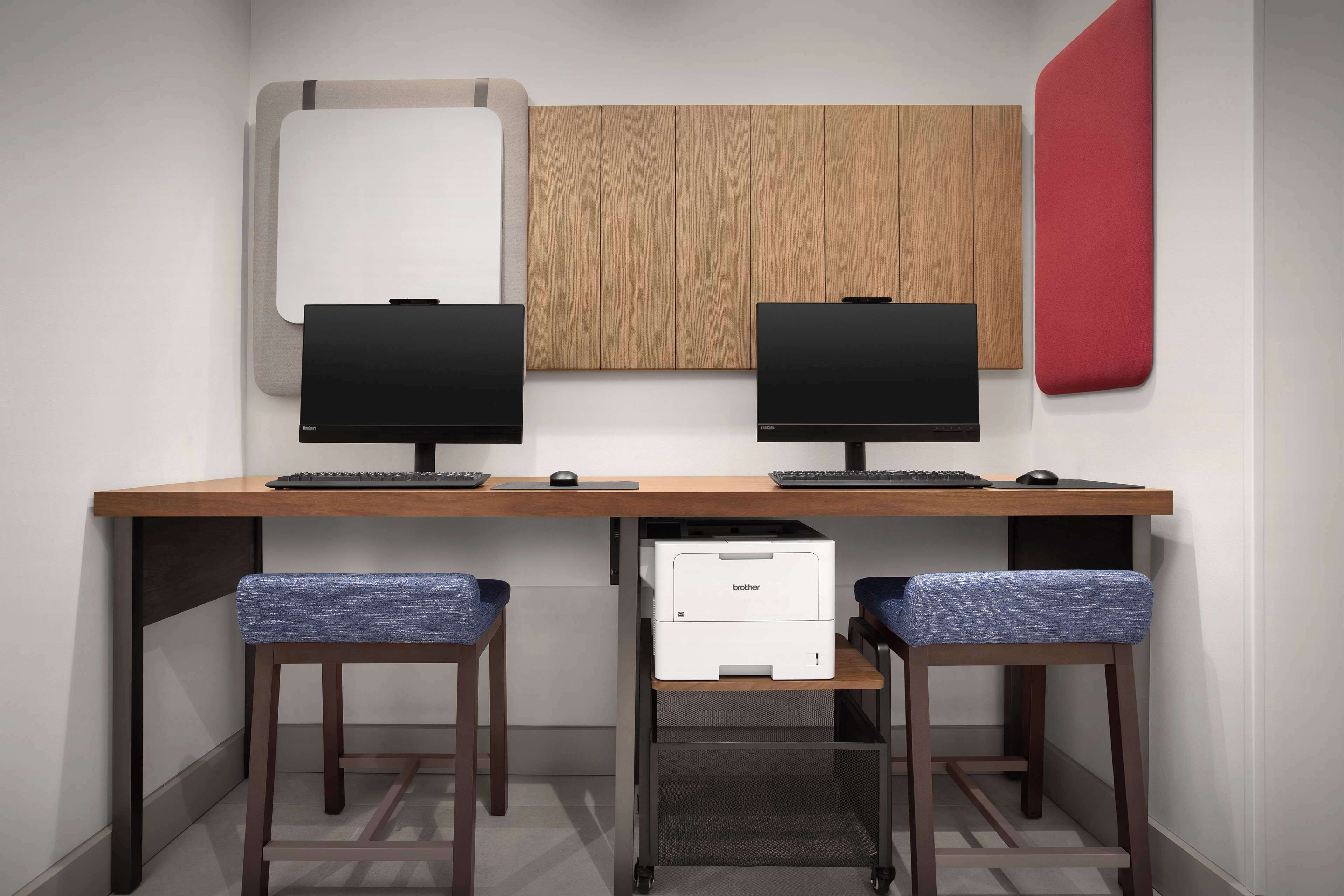 A workspace with two monitors, a printer, and a desk with a chair.