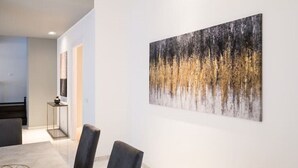 A modern interior with a dining area featuring a table and chairs, a hallway with a painting on the wall, and a staircase leading to another level. - Spacious penthouse with gym in historic building, near the Colosseum (Roma)