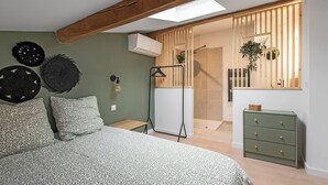 A bedroom with a bed, a bedside table, a dresser, and a skylight. - Le Blackwood (Mazamet)