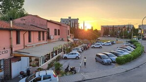Un parking rempli de voitures, un bâtiment sur lequel on peut lire l’inscription « RESTAURANT », et un coucher de soleil en arrière-plan.
