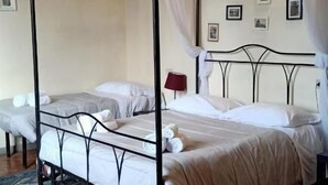 Un lit à baldaquin à quatre poteaux, avec du linge de lit blanc, une lampe rouge et des tableaux encadrés accrochés au mur.