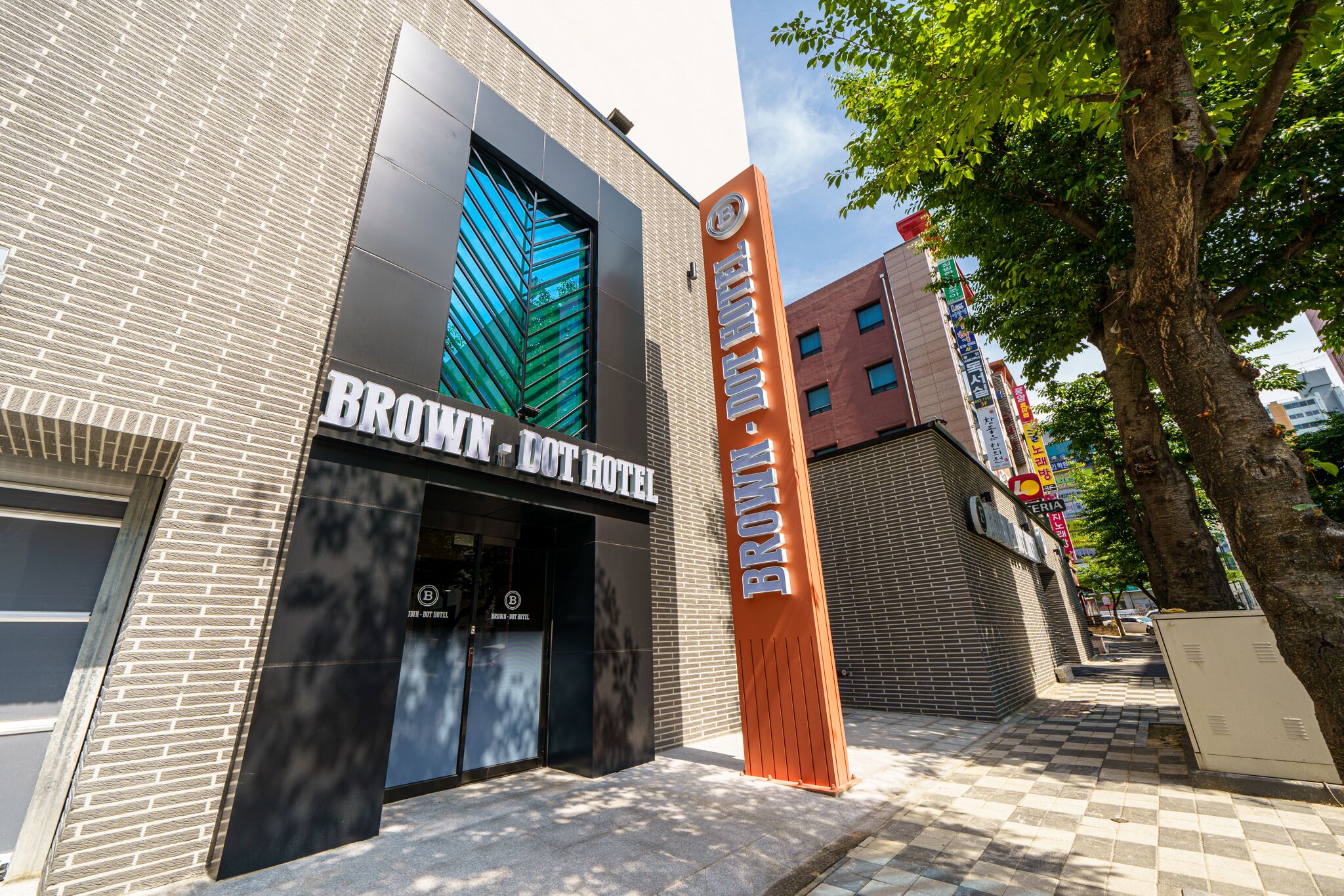 The exterior of the Brown - Downtown Hotel with a modern facade, large windows, and a prominent sign.
