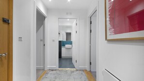 Un couloir menant à une salle de bain équipée d’un lavabo et d’un miroir.
