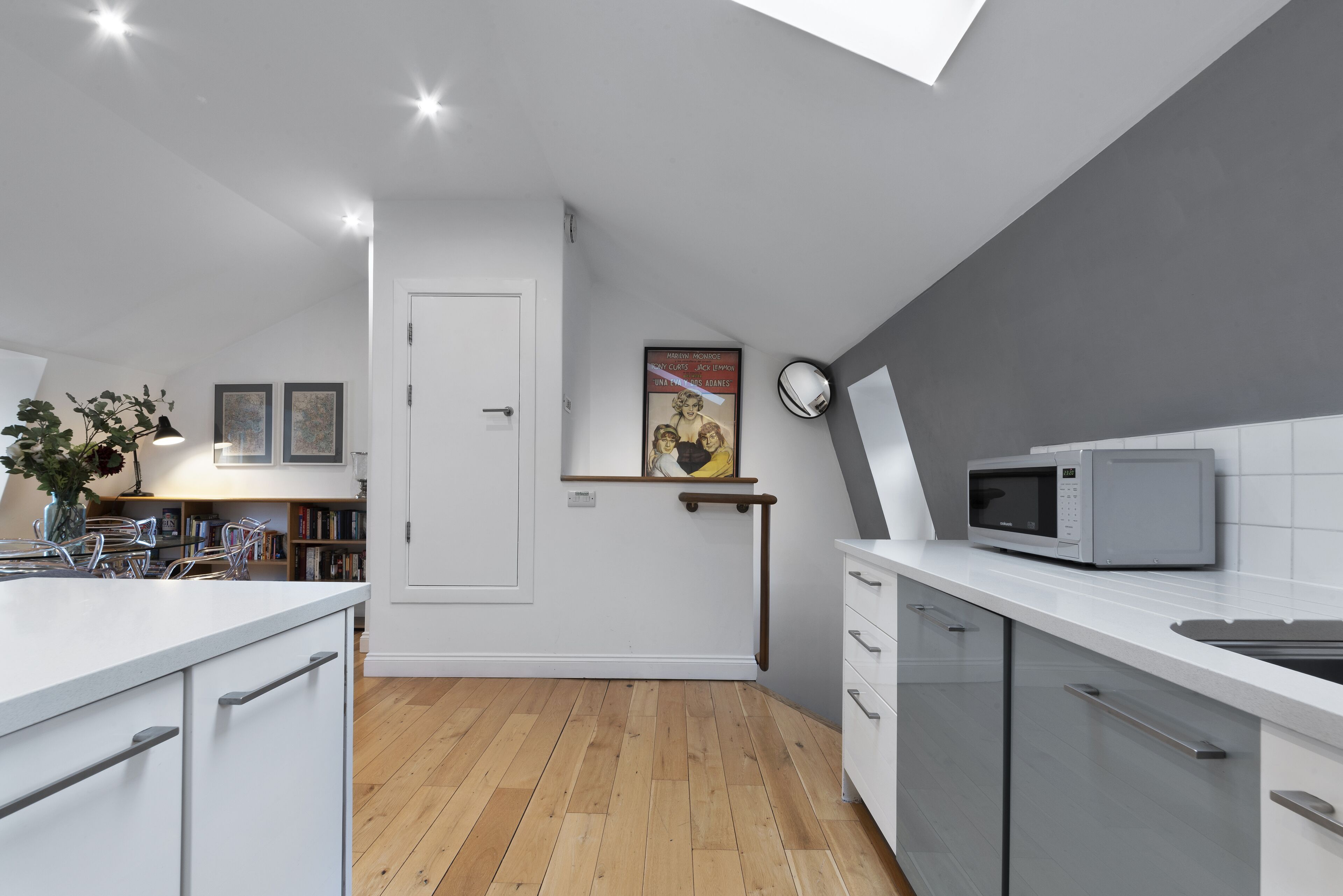 Une cuisine moderne avec des meubles blancs, un four à micro-ondes et un plancher en bois.