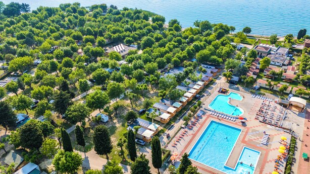An aerial view of a resort with multiple bungalow-style accommodations, a central swimming pool, and a beach area. - Baia Holiday Gasparina (Castelnuovo del Garda)