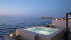 A rooftop pool with a view of the sea and a distant cityscape.
