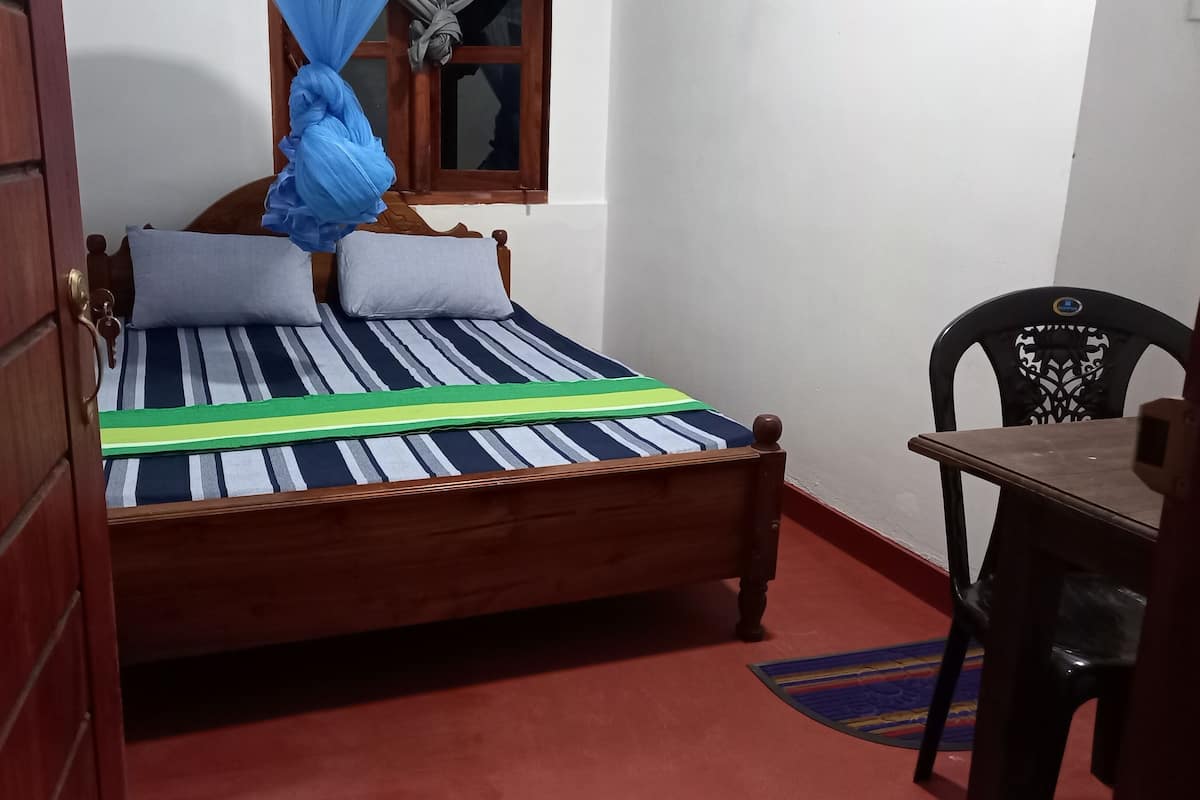 Un lit simple avec une couvre-lit à rayures, deux oreillers et un rideau bleu.