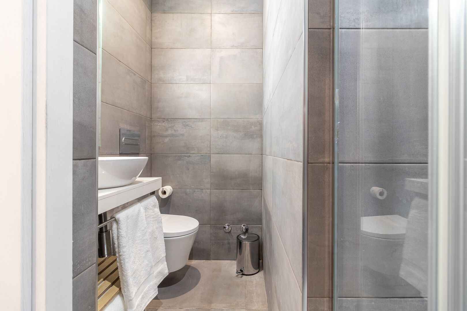 Et moderne badeværelse med bruser, toilet og håndvask.