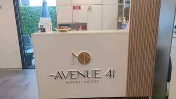 Una reception con la scritta "Avenue 41 Guest House", un logo, una piccola ciotola e un dispenser d'acqua.