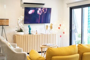 A modern living room with a sofa, a TV mounted on the wall, a potted plant, and a decorative sculpture. - Avenue 41 Guest House (Faro)
