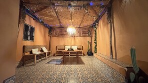 A room with a patterned floor, wooden furniture, a hanging light fixture, and a cactus plant.