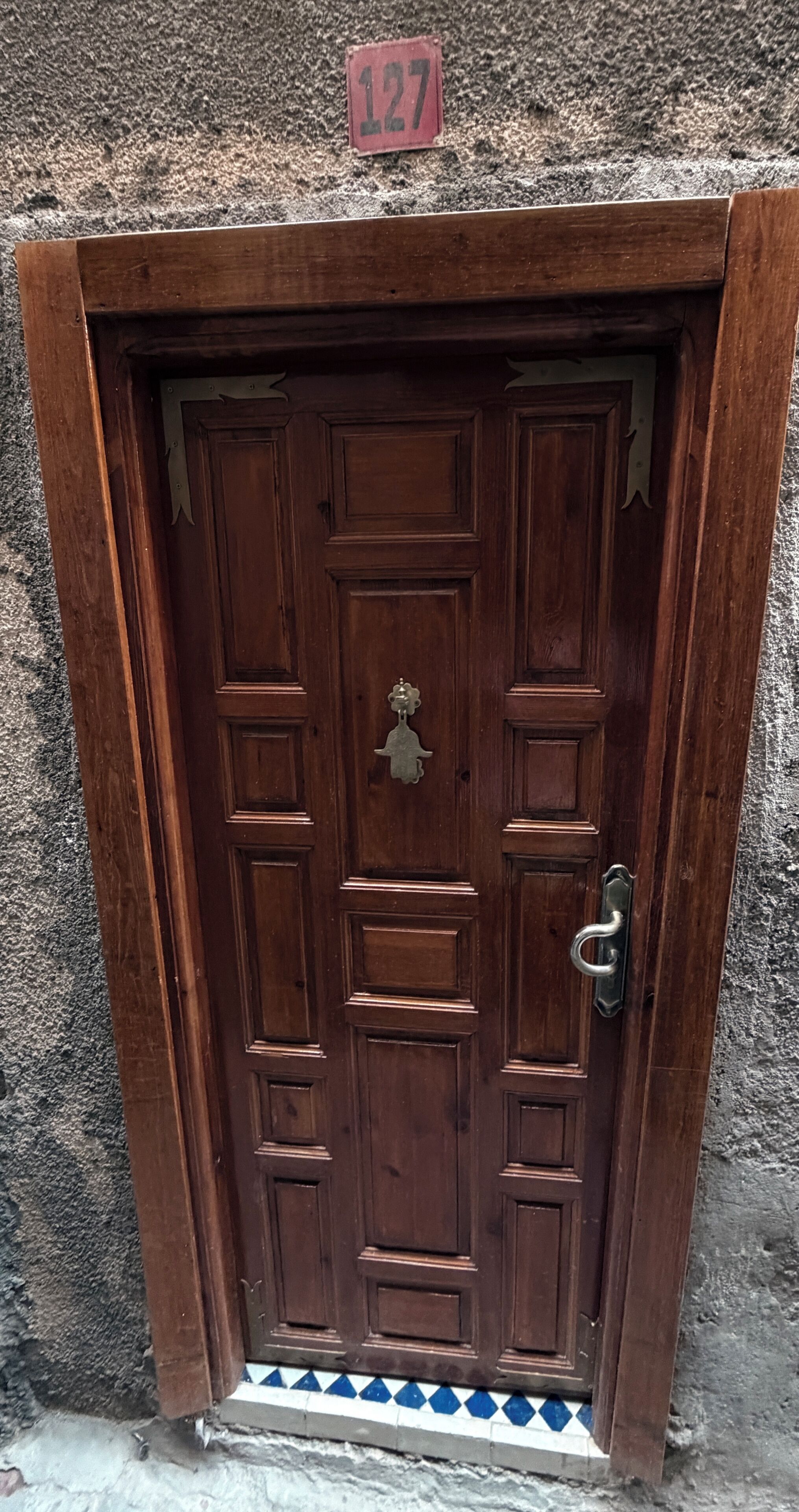 Une porte en bois avec une poignée en métal et un heurtoir en laiton.