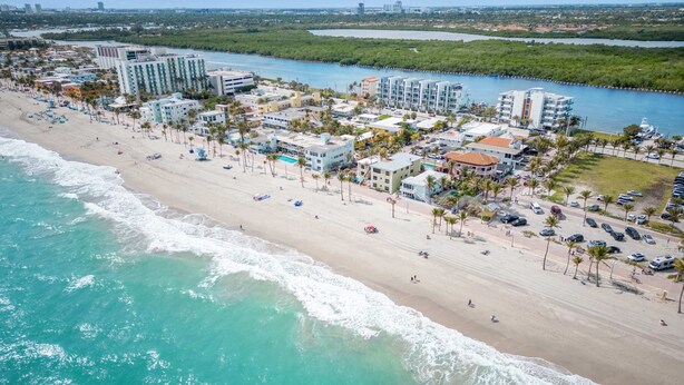 An aerial view of a coastal hotel area with beachfront properties, a sandy beach, and a river. - Beach Paradise : Family-Friendly + Free Parking (Hollywood)