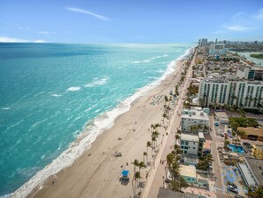 Un paysage urbain côtier avec une plage, des bâtiments et un ciel dégagé.