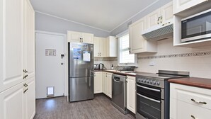 Una cocina moderna con electrodomésticos de acero inoxidable, armarios blancos y encimera de madera.