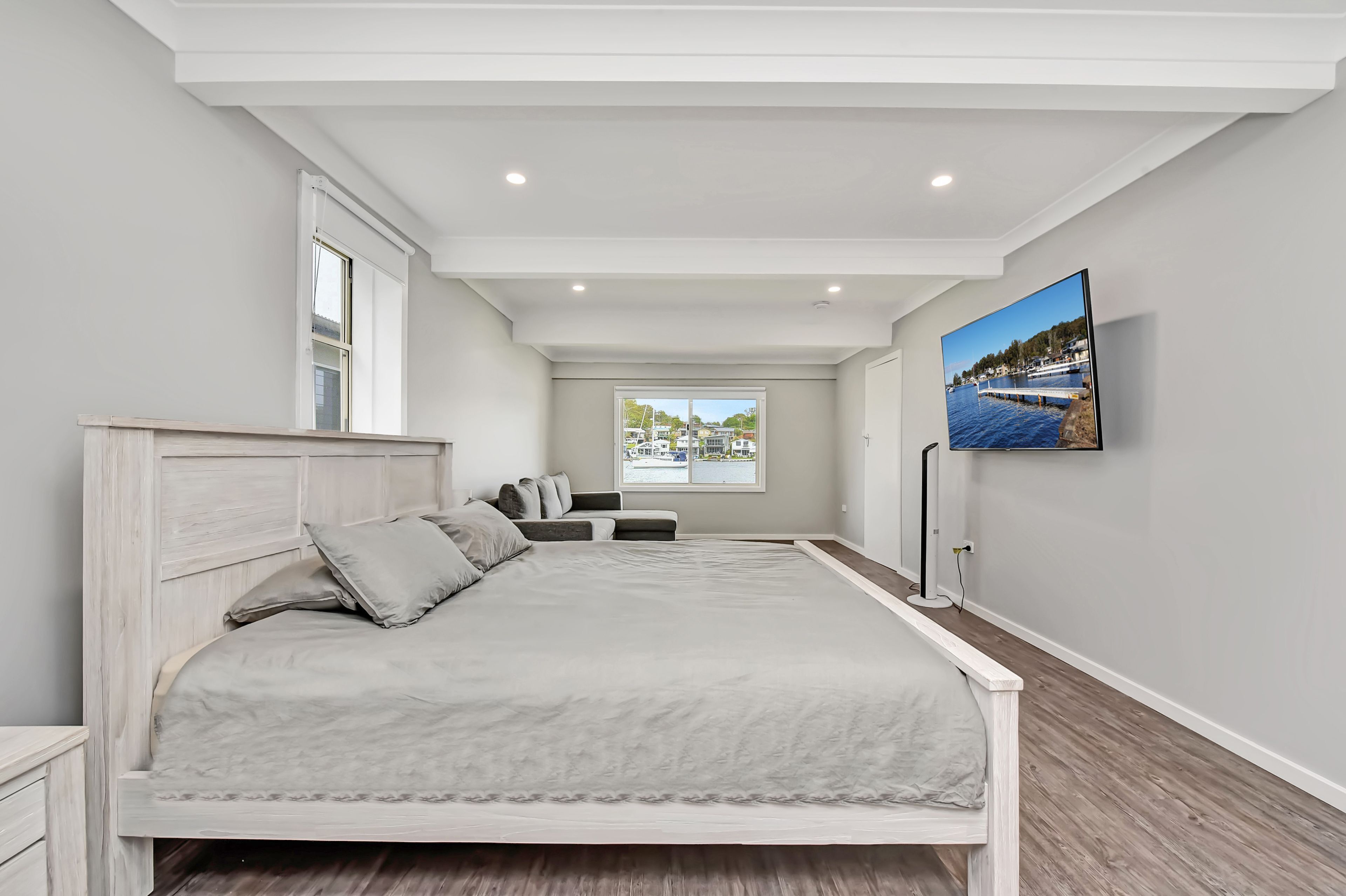 A bedroom with a bed, a TV, a window with a view, and a ceiling with recessed lighting.