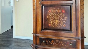 Un armari de fusta amb treballs florals detallats, ubicat en una habitació amb una porta i un interruptor de llum a la paret.