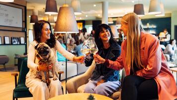 Un grupo de personas brindando con copas de vino en un espacio interior moderno con lámparas colgantes.