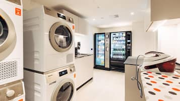 A laundry room with multiple washing machines, a refrigerator stocked with beverages, and a polka dot tablecloth.